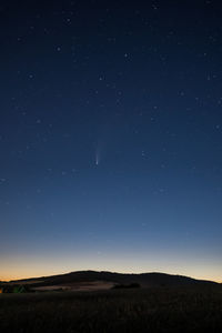 Scenic view of landscape against sky at night with the comet neowise