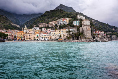 Buildings by sea against sky in town