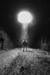 Rear view of man walking in illuminated tunnel