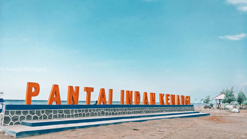 Text on beach against clear blue sky