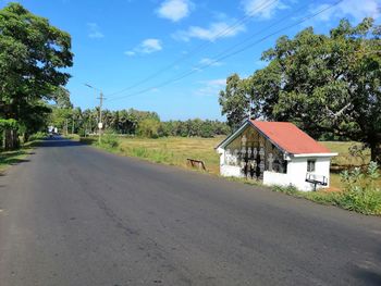 Road amidst trees and buildings against sky
