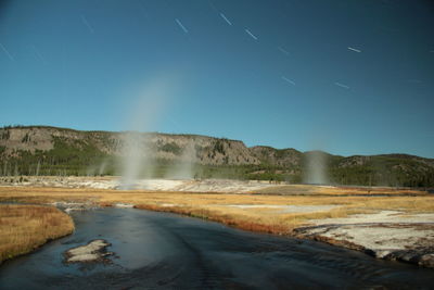 The firehole river flowing towards biscuit basin at night under the stars lit by the moon light. 