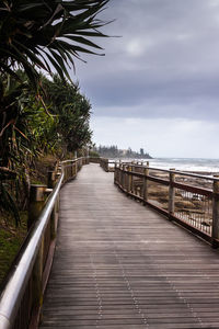 Surface level of wood paneled jetty against clouds