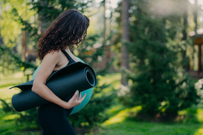 Side view of woman standing against trees