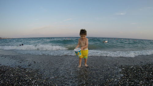 Rear view of boy on beach against sky