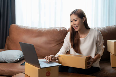 Young woman using digital tablet on sofa at home