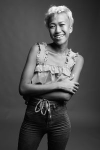 Portrait of smiling young woman against gray background