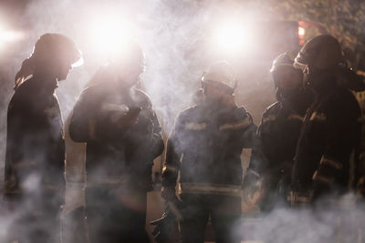 Firefighters discussing while standing on land
