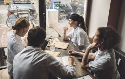 High angle view of male and female chefs discussing at table in restaurant