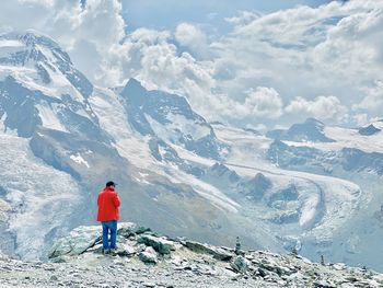 Rear view of woman standing on snowcapped mountain