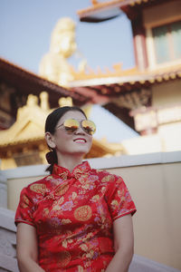 Asian pretty woman wearing red chinese suit standing outdoor