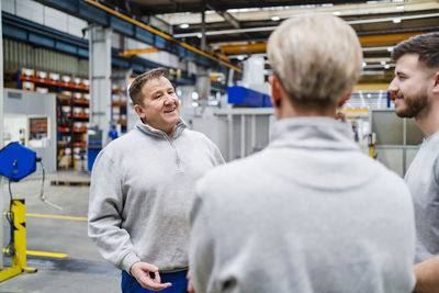 Smiling employee discussing with colleagues in industry