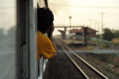 Rear view of man looking through train window