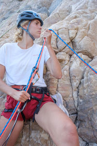 Woman holding ropes while standing against rock