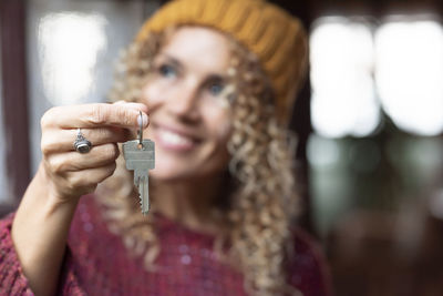 Smiling woman holding key while looking away
