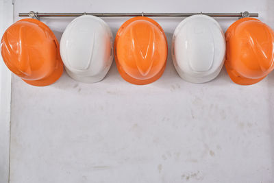 Close up hard hats hanging on hook against the dirty white wall.