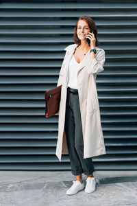 Young woman standing against wall