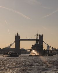 Silhoette of tower bridge over river at sunset