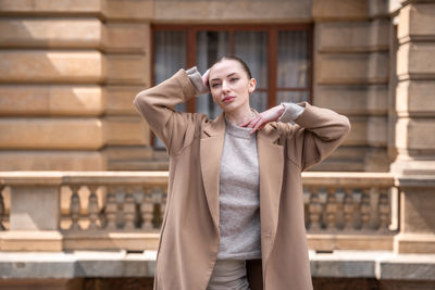 Portrait of young woman standing against wall