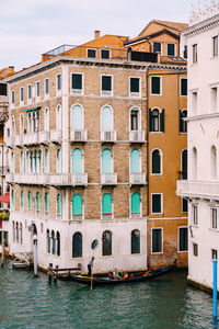 Buildings by canal against sky in city