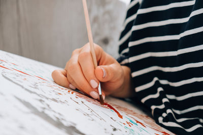 Painting on canvas by numbers and numbered jars of paint. woman draws with a brush painting 