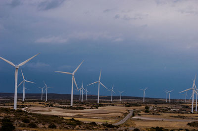 Wind turbines on field against sky