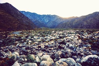 Scenic view of pebbles and mountains against clear sky