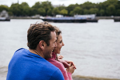 Happy man embracing woman at riverbank