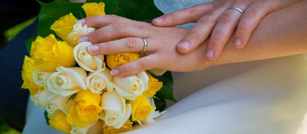 Close-up of bride and groom hand with bouquet