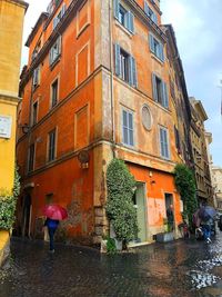 Rear view of wet walking on building during rainy season