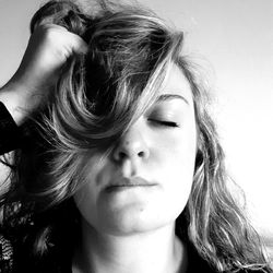 Close-up of beautiful woman with closed eyes and hand in hair