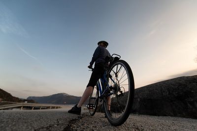 Rear view of man riding bicycle on road against sky