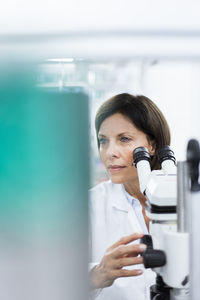Mature female scientist with microscope at laboratory
