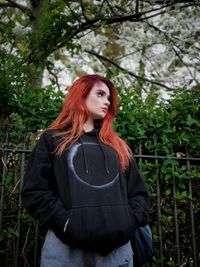 Portrait of young woman standing against tree