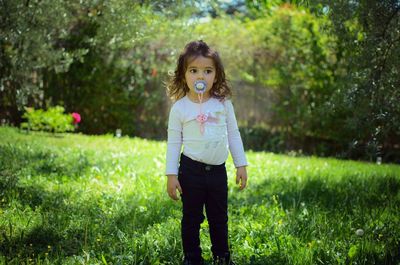 Full length portrait of smiling girl standing on grass