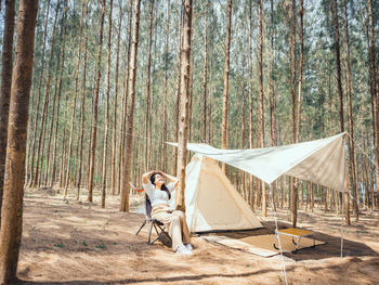 Happy asian teenage girl in front of camp tent. outdoor activity. 