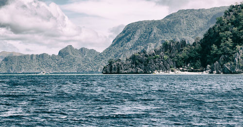 Scenic view of sea by mountains against sky