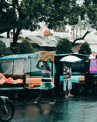 People on wet street in city during rainy season