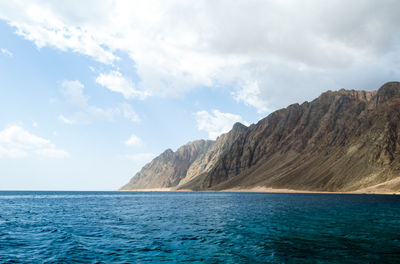 Scenic view of sea and mountains against sky