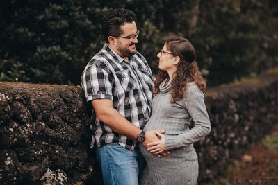 Young couple standing against trees