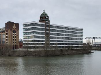 Building by river against sky in city