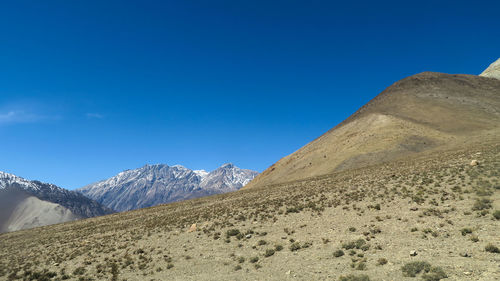 Scenic view of arid landscape against clear blue sky