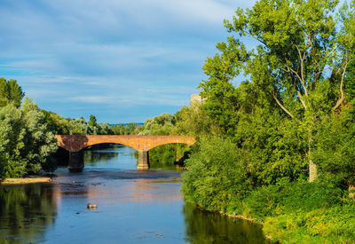 Arch bridge over river against sky