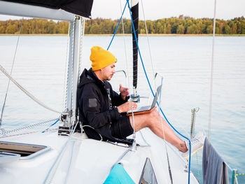 Person working with laptop on a sailing yacht during sailing by lake, remote work concept person