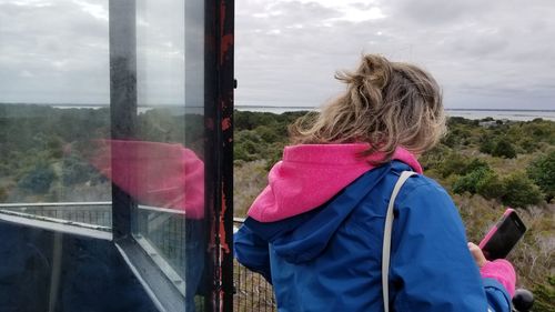 Rear view of woman looking through glass window