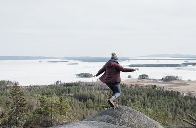 Woman jumping rocks whilst hiking up a mountain in sweden