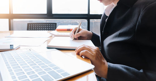 Midsection of man using laptop on table