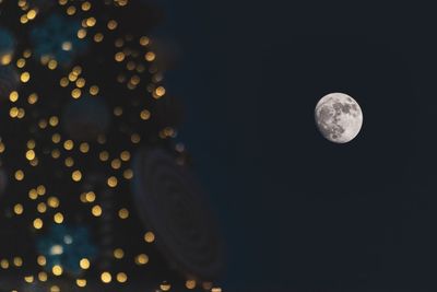 Defocused image of illuminated lights against sky at night