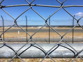 Close-up of chainlink fence against airport runway