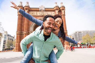 Portrait of smiling man with arms outstretched standing on street